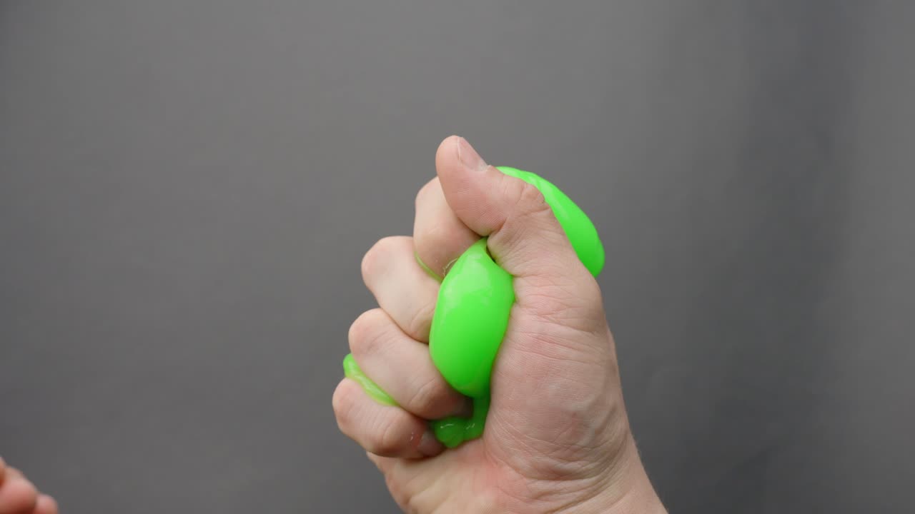 ASMR: Caucasian hands knead green slime, moving it right to left in soothing repetitive motion.