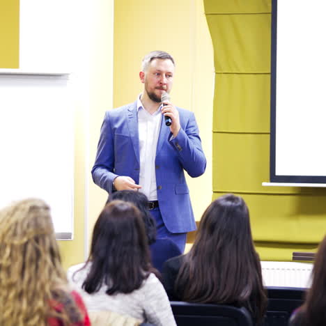 professional coach speaking into the microphone on stage in auditorium. businessman shares his knowledge with the audience during the business forum.
