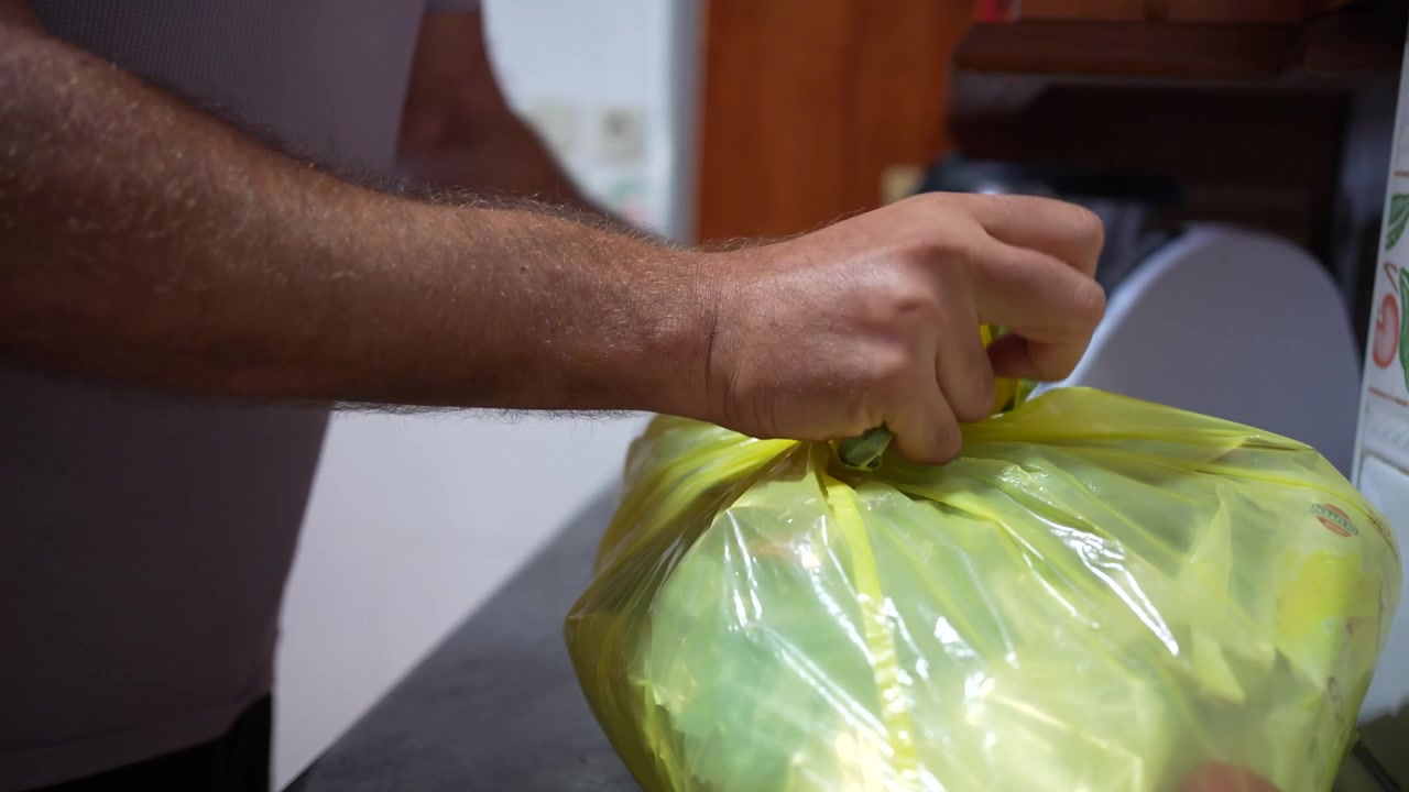 El proceso de sellar eficazmente una bolsa de basura de plástico amarilla para la eliminación de residuos