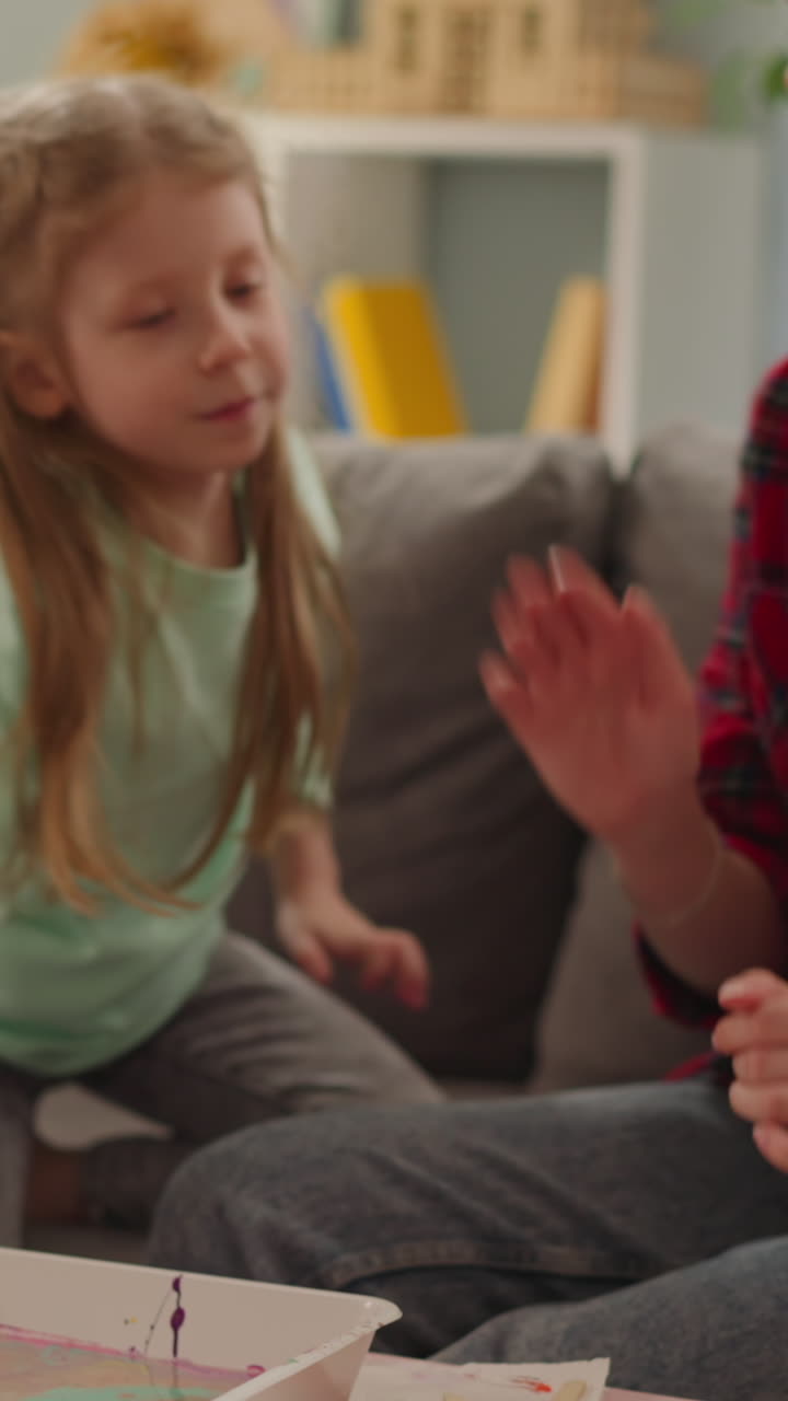 Sisters finish eggs coloring for Easter and give high five in living room slow motion. Ebru design technique and Christian holiday traditions