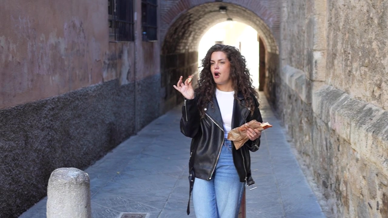 Una donna vestita con un'elegante giacca di pelle passeggia tranquillamente lungo un vicolo storico.