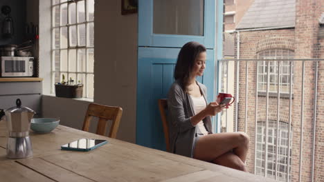 morning coffee for mixed race woman happy at home in pajamas using smart phone