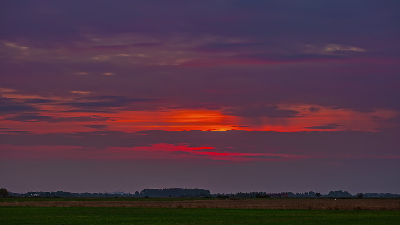 Time lapse of a colorful sunrise over the farmland fields and forest - dawn of a new day