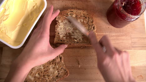 Aufnahme-Aus-Der-Perspektive,-Die-Zeigt,-Wie-Eine-Person-Marmelade-Auf-Toast-Verteilt