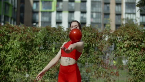 woman juggling a red ball outdoors