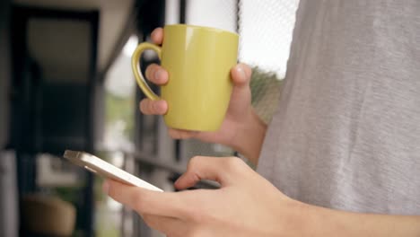 man having coffee while using mobile phone at home 4k