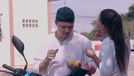 handsome guy sits on motorbike and eats laughing in summer