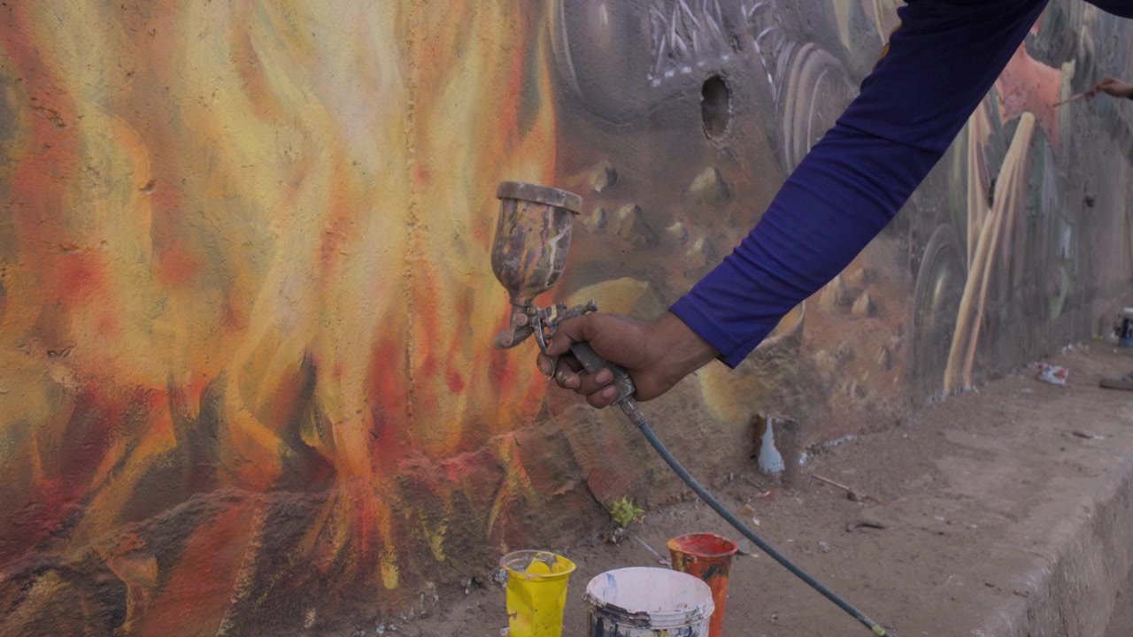 Pintor profissional pulverizando tinta em uma parede com uma pistola de pintura, alcançando uma cobertura suave e uniforme durante o trabalho de renovação.