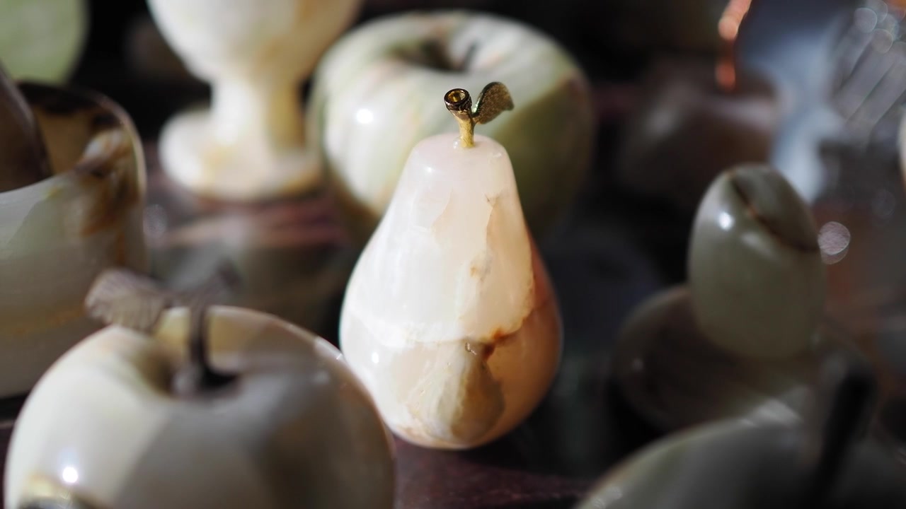 Gros plan d'une élégante figurine de poire en onyx avec d'autres fruits en pierre