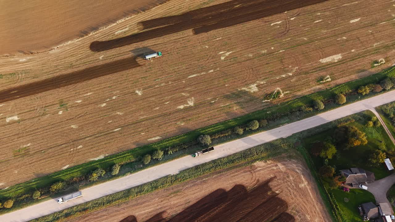 Drone shot of a manure spreader working on a large brown farm field
