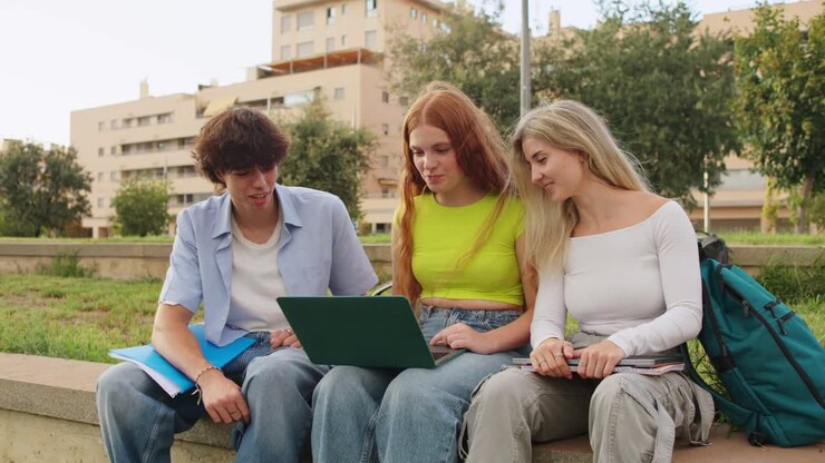 Gruppo di studenti che studiano insieme all'aperto con un portatile