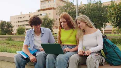 Group of students studying together with a laptop outdoors