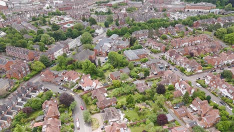 Aerial-view-of-charming-red-brick-suburbs,-showcasing-quaint-residential-architecture-and-lush-greenery-in-Exeter,-UK