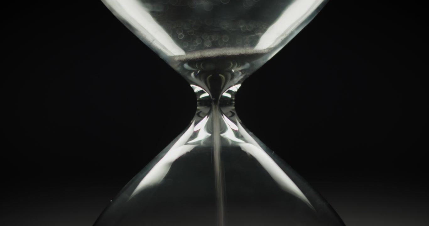 Black sand pouring inside sand clock