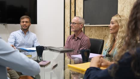Group of coworkers talking in boardroom at office