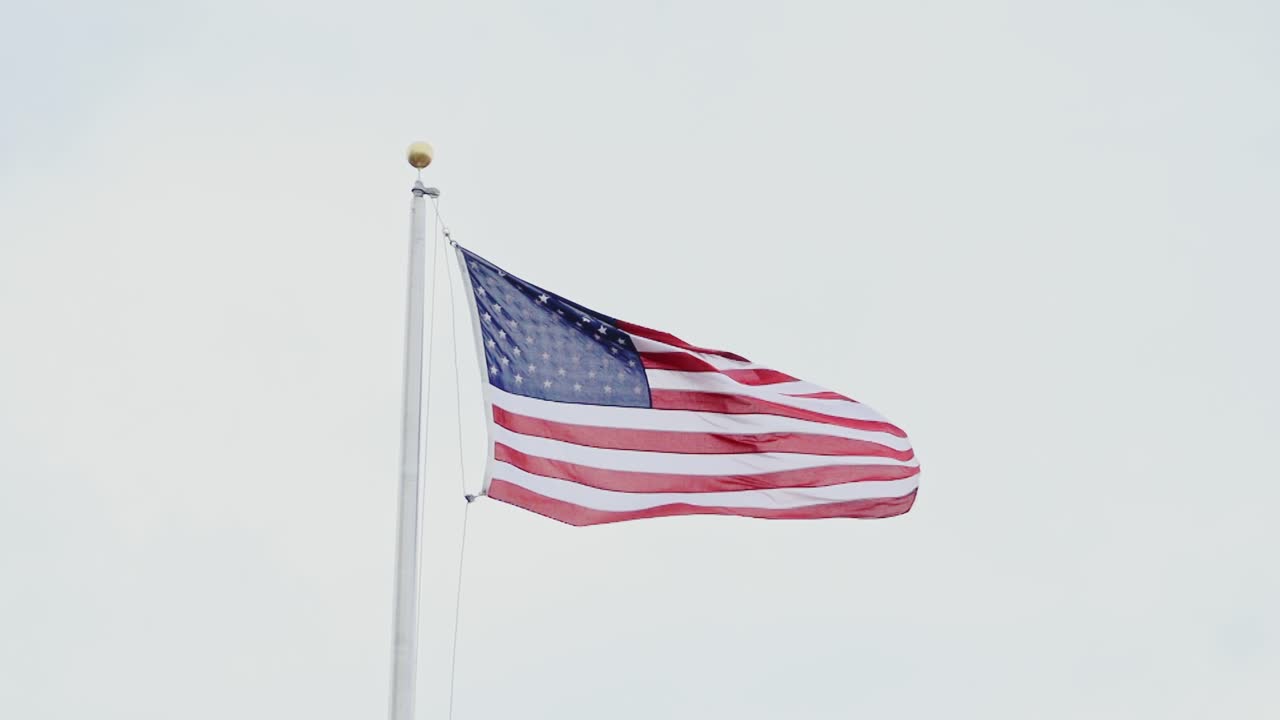 Slow motion close-up, American waving flag, patriotism, freedom, white gray sky