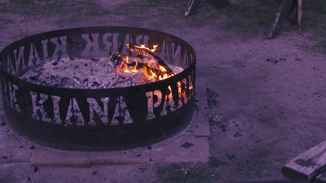 Uma aconchegante fogueira brilha calorosamente em um braseiro de metal, ideal para encontros ao ar livre.