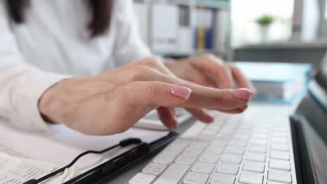 la mujer está escribiendo en el teclado de la computadora portátil en primer plano