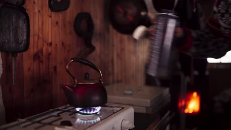 person grabs water flask from the kitchen with water heating on the stove