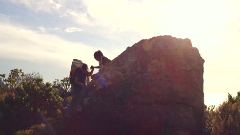 silhouette of a couple hiking lending a helping