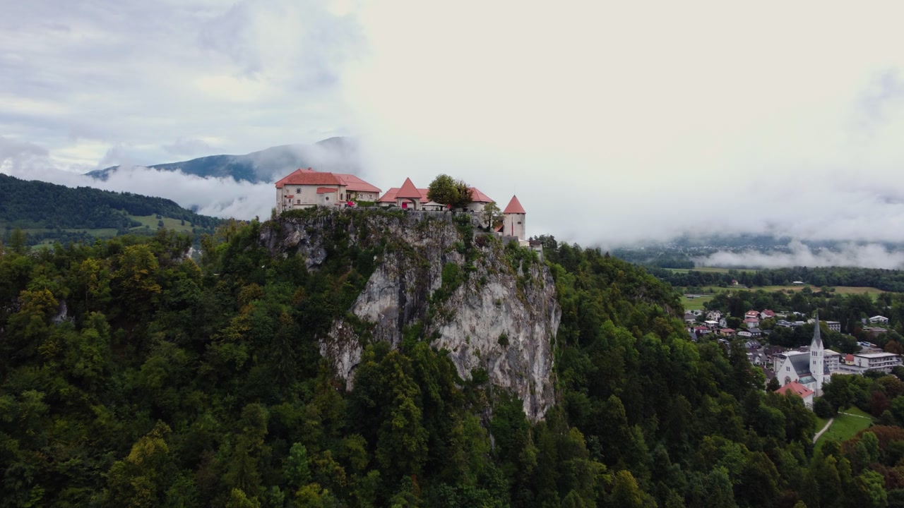 AERIAL Approaching Shot of Bled Castle in Lake Bled, Slovenia on a Cloudy Day