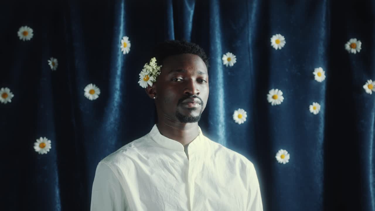 Ritratto di uomo afroamericano contro una tenda blu con fiori di margherita