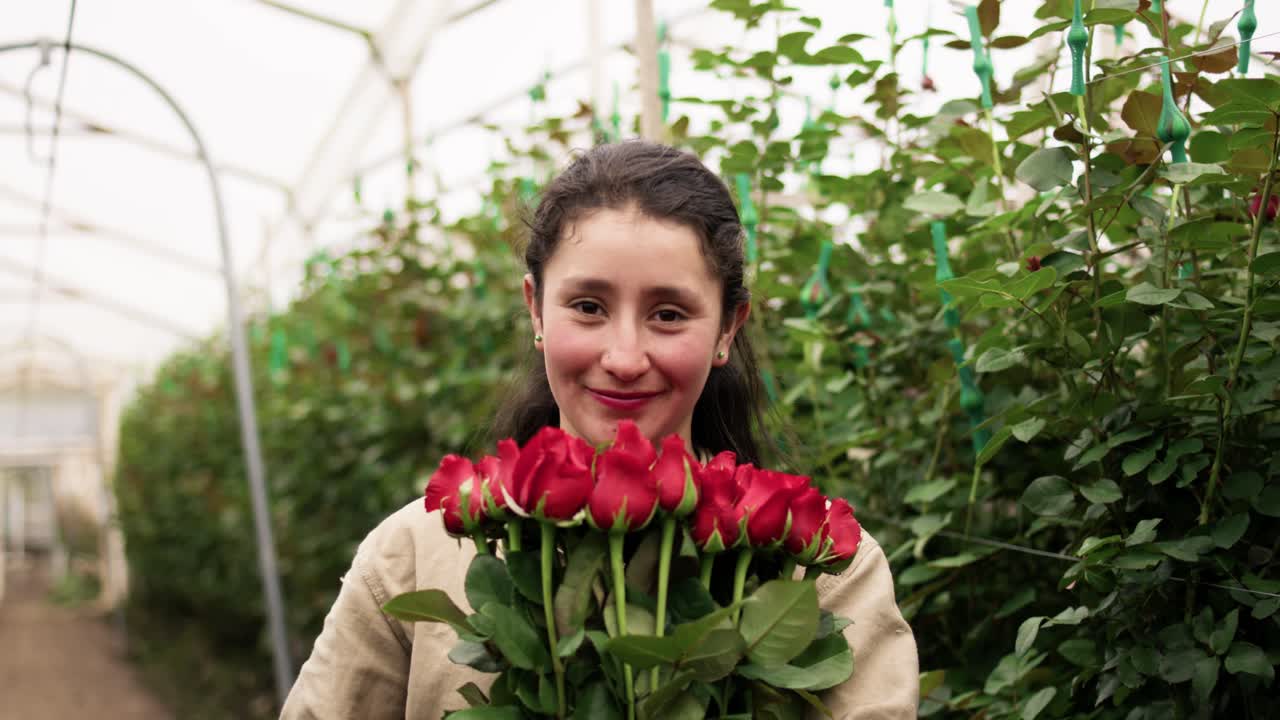 Friendly brown-haired girl smiling at the camera while holding a bouquet of red roses