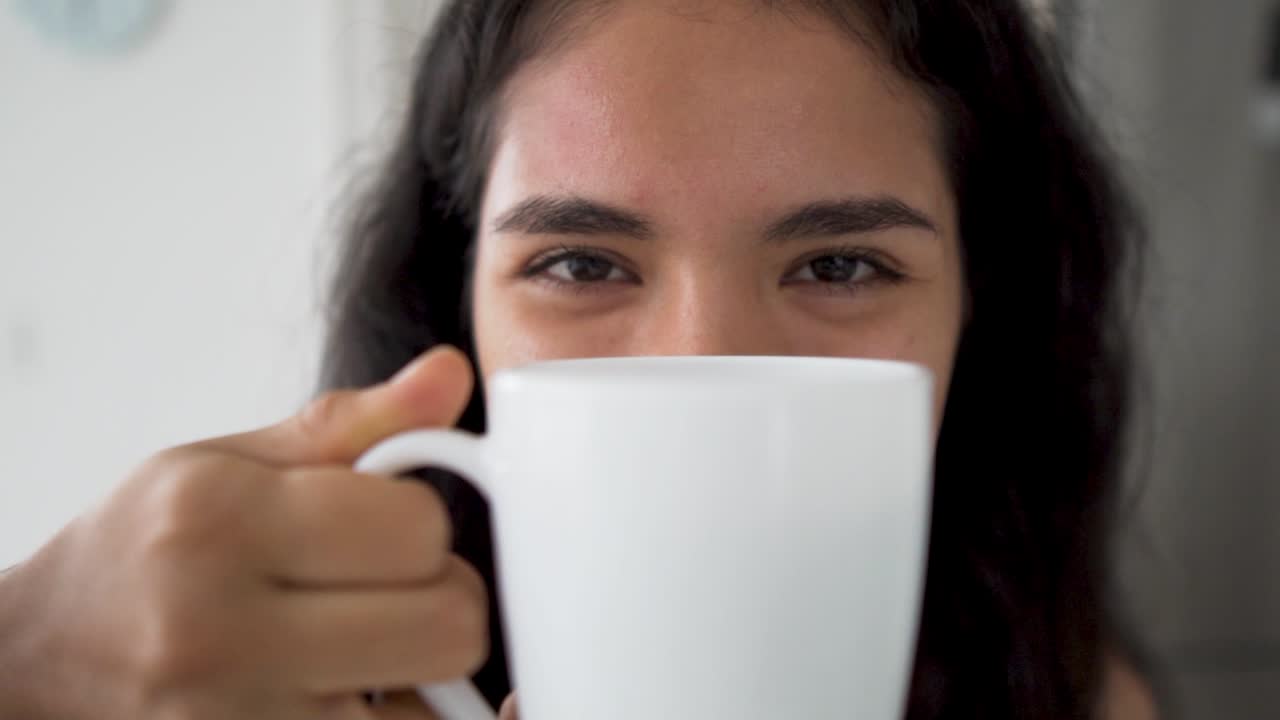 검은 머리를 가진 아름다운 젊은 라티나 여성은 맛있는 커피 한잔을 즐긴다