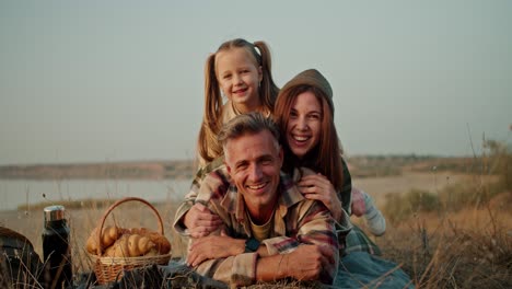 Trío-Familiar-Feliz:-Hombre-Moreno-De-Mediana-Edad,-Su-Esposa-Y-Su-Pequeña-Hija-Relajándose,-Divirtiéndose-Y-Posando-Durante-Sus-Vacaciones-En-Un-Picnic-Fuera-De-La-Ciudad-En-Verano