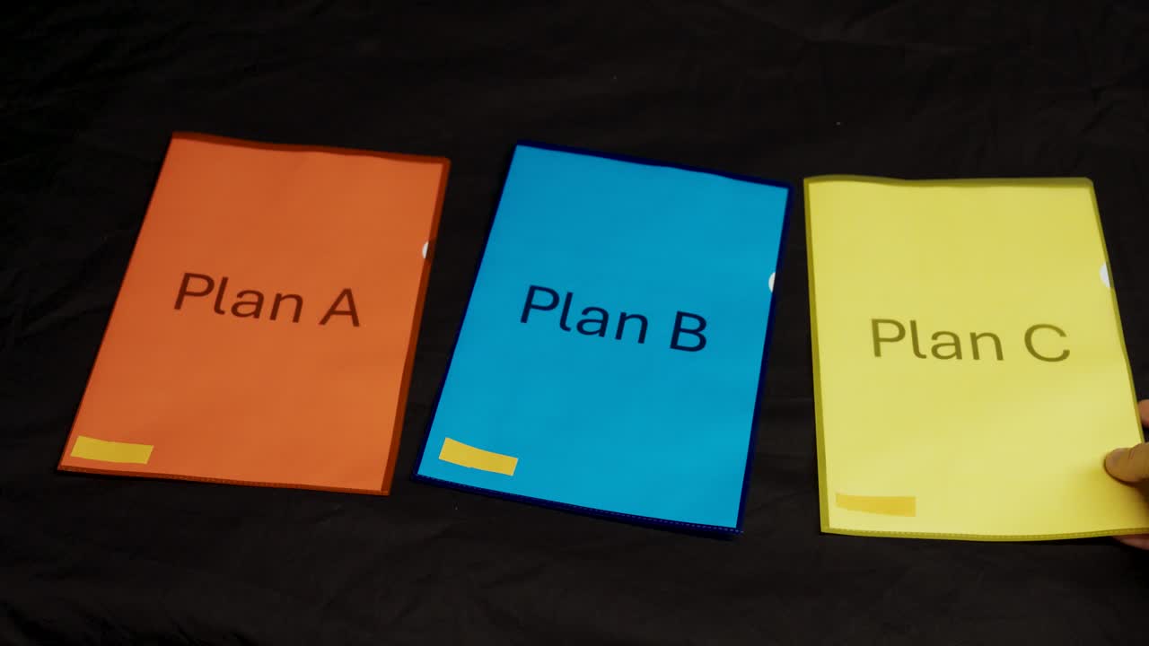 Three folders labeled Plan A, Plan B, and Plan C are laid out in a row on a black surface, symbolizing organization, planning, and decision strategy