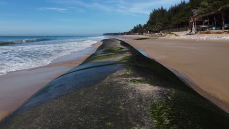 Low-aerial-flying-over-geotubes-on-beautiful-Vietnamese-beach-in-danger