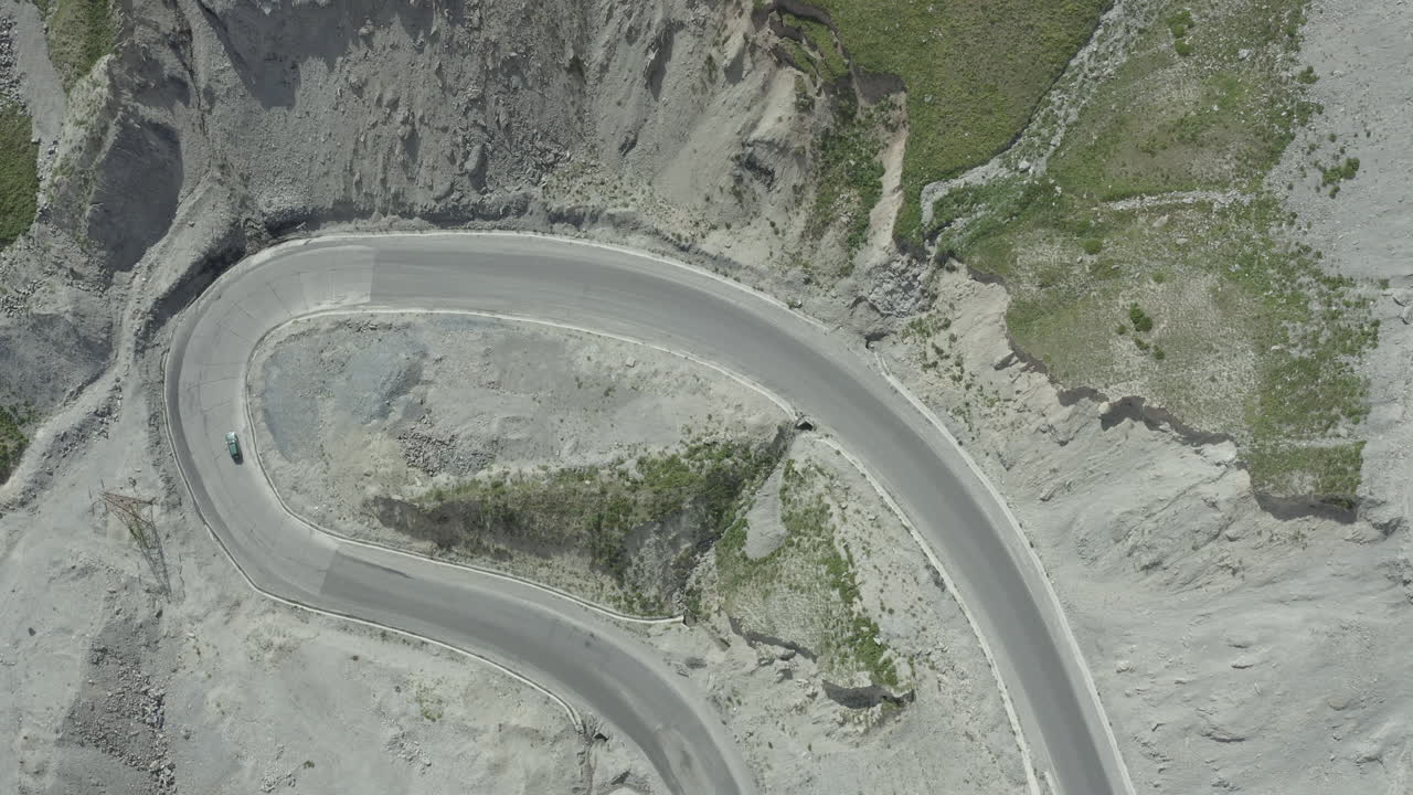 Winding road through a mountainous terrain with a car driving, Kyrgyzstan