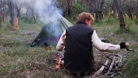 A-close-up-shot-of-a-bushman-building-a-fire-out-in-the-Australian-bush-while-camping