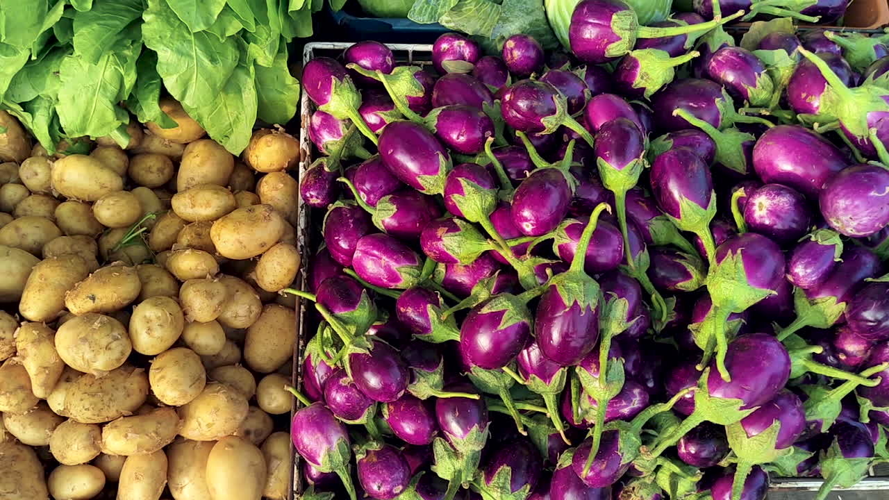 Close-up of fresh eggplants and potatoes at street market. Ideal for food retail, grocery shopping, organic produce, healthy eating and farm-to-table concepts