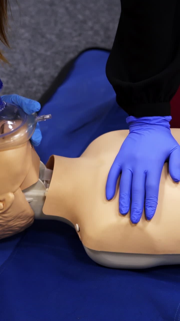 Training reanimation procedure on a mannequin. People use breathing apparatus on a dummy's face during practice course. Training for giving first aid to a patient. Vertical video