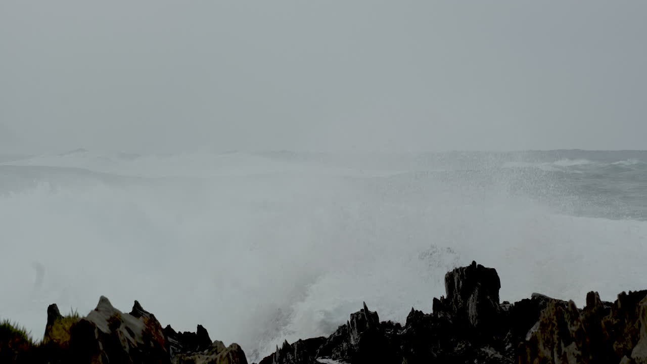 Powerful wave crash over jagged rocks on coastline of Storms River mouth. Slomo