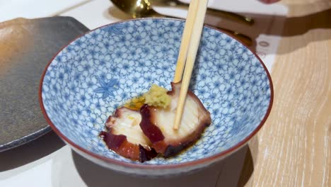 chopsticks picking up squid from a bowl