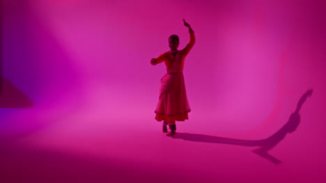 camera moves through studio equipment to show female kathak dancer wearing traditional indian dress dancing 2