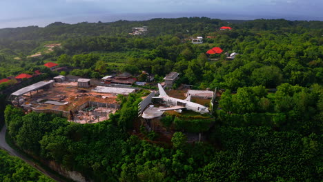 retired passenger jet plane perched between houses on jungle cliff