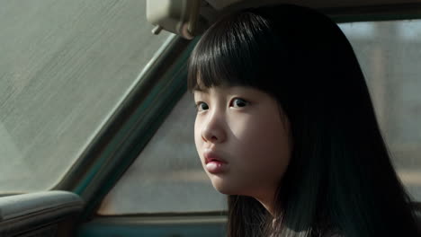 a young girl looking out the car window