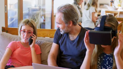 Padre-Usando-Computadora-Portátil-Mientras-Su-Hija-Habla-Por-Teléfono-Móvil-En-La-Sala-De-Estar-4k