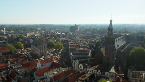 Sint-Jan-Church-And-Old-Town-Hall-Building-In-Downtown-Gouda,-Netherlands-During-Daytime---aerial-drone-shot