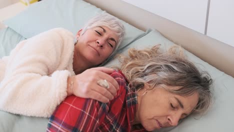 Affectionate lesbian couple laughing in bed