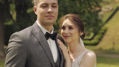 newlyweds, bride woman lying on her husband shoulder and looking at camera, happy wedding couple