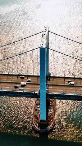 transport moving quickly by the throgs neck bridge. aerial view on the east river and suspension bridge on sunny day.