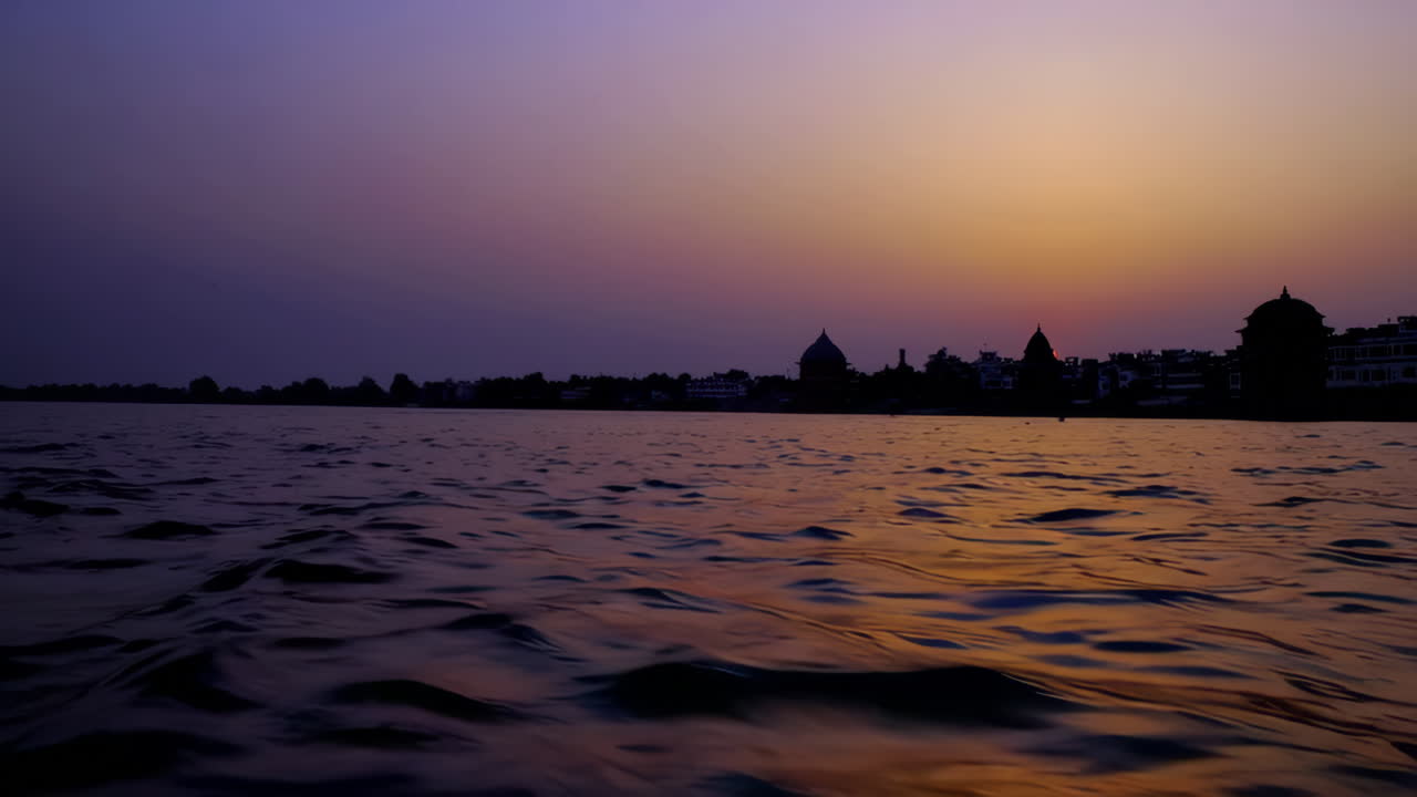 Vibrant sunset over a river with a silhouetted city skyline