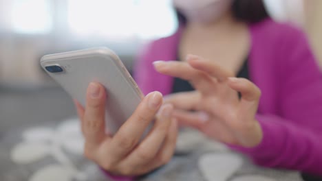 una mujer en primer plano sentada en un sofá sosteniendo un teléfono inteligente para comprar en línea en casa
