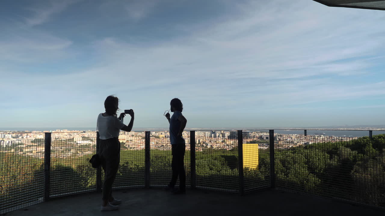 dos personas haciéndose una foto con lisboa de fondo