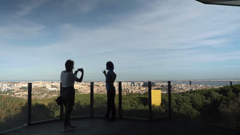 two persons taking a photo with lisbon in the background