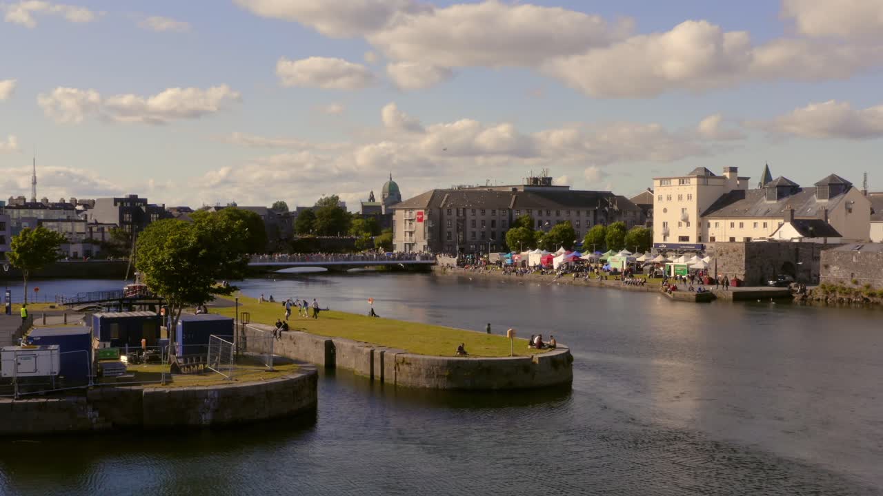 Bustling Riverfront Scene with Market Stalls and People in an Urban City